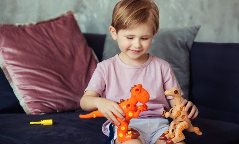 cute-boy-sitting-on-a-sofa-playing-with-his-dinosaur-toys